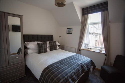 1 dormitorio con cama y ventana en By The Bay, en Cruden Bay