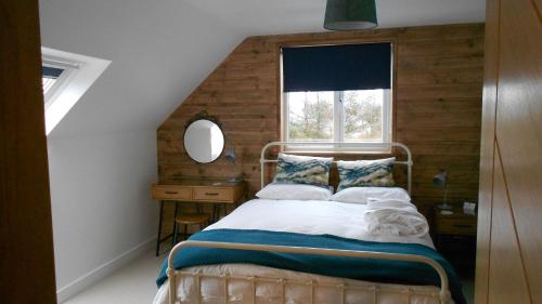 a bedroom with a bed with a window and a mirror at Breakish Escape B&B-near Broadford in Breakish