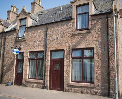 a brick building with windows and doors on a street at By The Bay in Cruden Bay