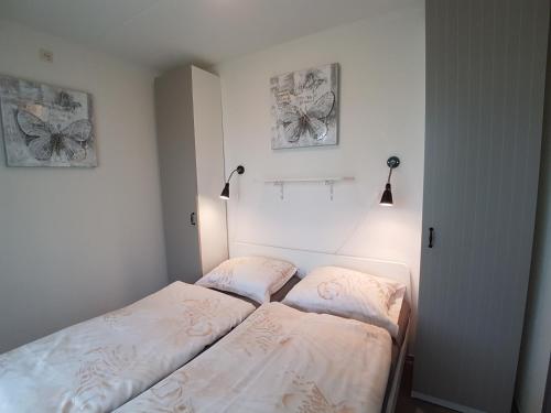 ヴェストカペレにあるZAND Bed by the Seaのベッドルーム1室(ベッド2台付)、壁にランプ2つ