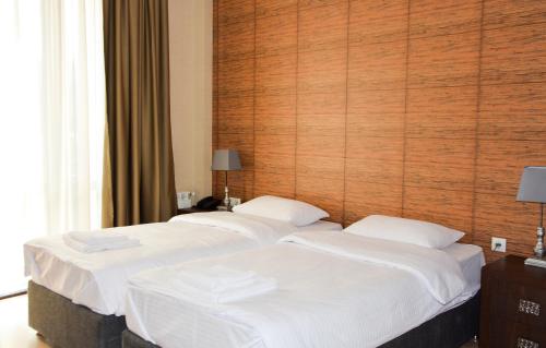 three beds in a hotel room with white sheets at Eleon Boutique Hotel in Tbilisi City