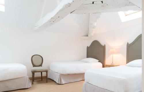 a bedroom with two beds and a chair at Château de Pierreclos in Pierreclos