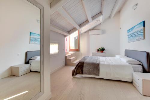 ein weißes Schlafzimmer mit einem Bett und einem Spiegel in der Unterkunft Residence La Fontaine in Lido di Venezia