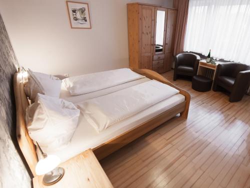 a bedroom with a bed with white sheets at Gästehaus Wein im Turm in Longuich