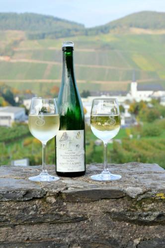 two glasses of white wine sitting next to a bottle of wine at Gästehaus Wein im Turm in Longuich