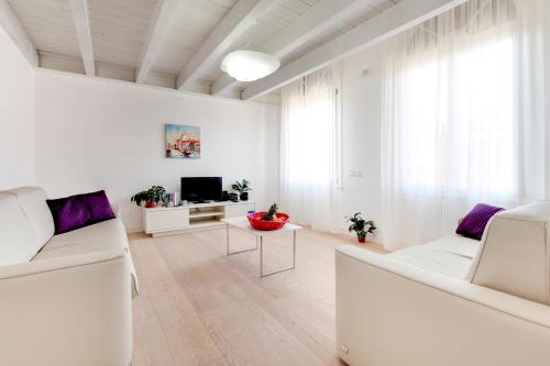 a white living room with white furniture and a tv at Residence La Fontaine in Venice-Lido