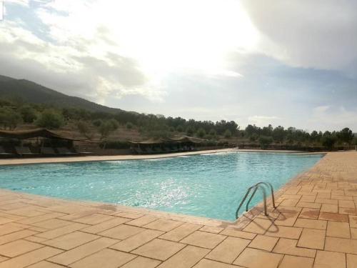 a swimming pool with blue water on a patio at Terres d'Amanar in Tahannout