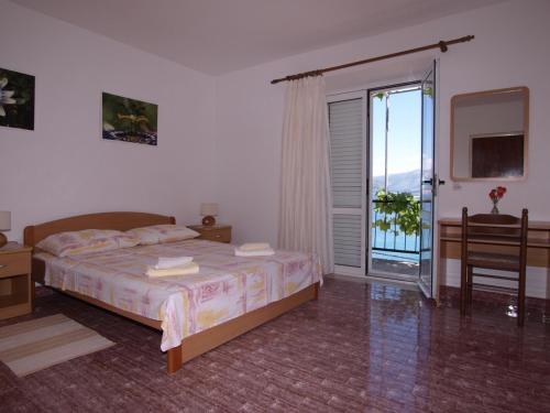 a bedroom with a bed and a sliding glass door at Apartments Skorin in Lumbarda