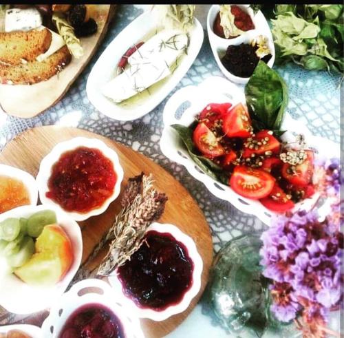 a table with a plate of food with tomatoes and other foods at Cunda Adali Pansiyon in Ayvalık