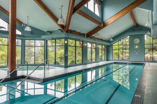 uma piscina interior com janelas de vidro e um tecto com vigas de madeira em Predator Ridge Resort em Vernon