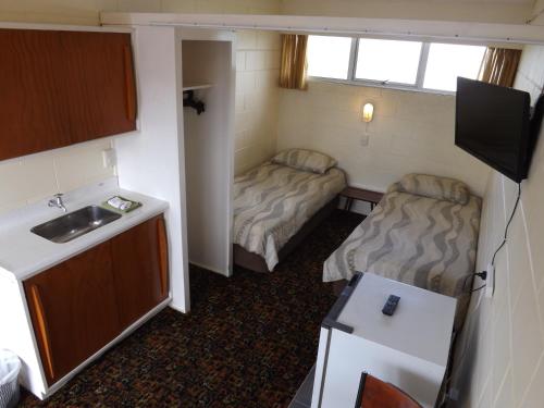 a small room with two beds and a sink at Whangarei Central Holiday Park in Whangarei