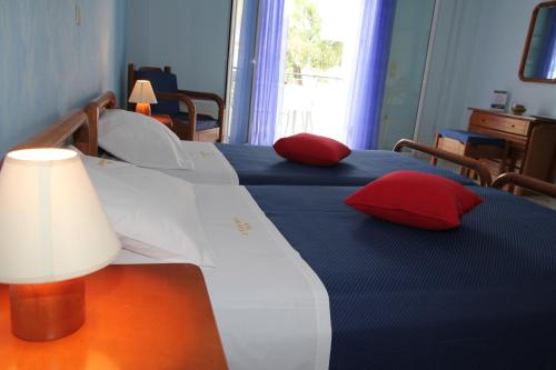 a bedroom with two beds with red pillows at Saint Nicholas Beach Resort in Dassia
