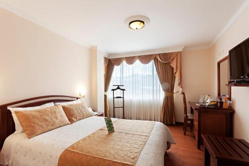 帕斯托的住宿－費爾南多廣場酒店，一间卧室配有一张床、一张书桌和一个窗户。