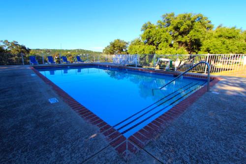 a swimming pool with blue water and a fence at The Shores at Lake Travis, a VRI resort in Lago Vista
