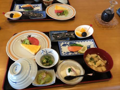 een dienblad met borden en kommen met voedsel bij Tamaki Ryokan in Kumamoto