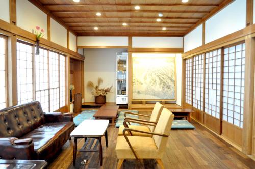 a living room with a couch and chairs and windows at Guest House Takazuri-KITA in Nanto