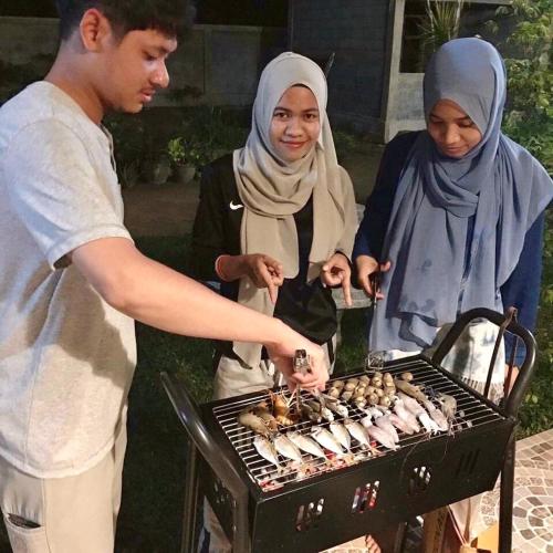 a group of people cooking food on a grill at Baan Chang Residence in Bang Sare