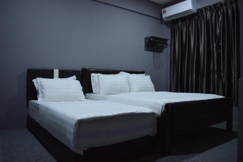 two beds in a bedroom with white sheets and pillows at Times Traveller Lodge 2 in Kota Belud