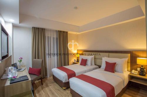 um quarto de hotel com duas camas e uma secretária em Orchardz Hotel Bandara em Tangerang