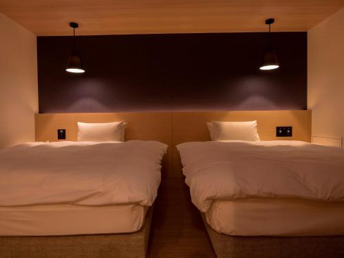 two beds sitting next to each other in a room at UAN kanazawa in Kanazawa