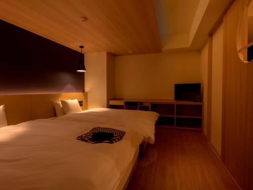 a bedroom with a white bed and a television at UAN kanazawa in Kanazawa