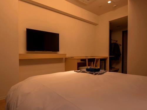a bedroom with a bed and a tv on the wall at UAN kanazawa in Kanazawa