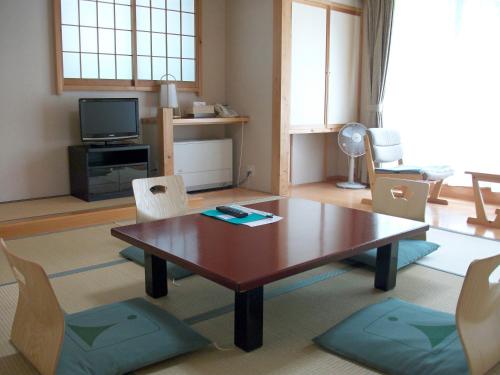 uma sala de estar com uma mesa de madeira e cadeiras em Kamikochi Nishi-itoya Mountain lodge em Matsumoto