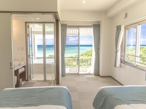 two beds in a bedroom with a view of the ocean at Seven Colors Ishigakijima in Ishigaki Island