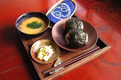 uma bandeja de madeira com pratos de comida numa mesa em Guest House Shimayado Aisunao em Naoshima