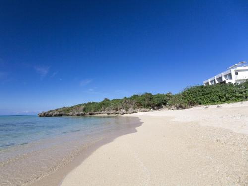 a sandy beach with a building in the background at Seven Colors Ishigakijima in Ishigaki Island