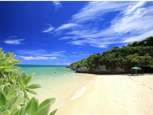 a beach with an umbrella and people in the water at Seven Colors Ishigakijima in Ishigaki Island