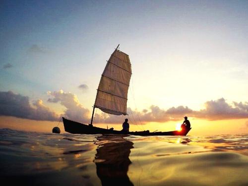 a man on a sail boat in the ocean at sunset at Seven Colors Ishigakijima in Ishigaki Island