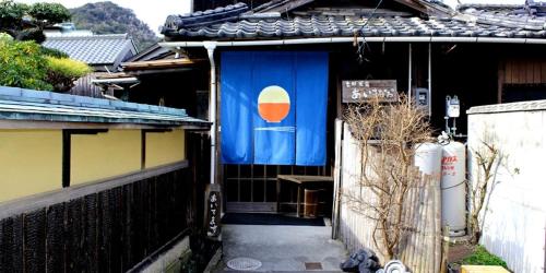 um edifício com uma bandeira ao lado em Guest House Shimayado Aisunao em Naoshima