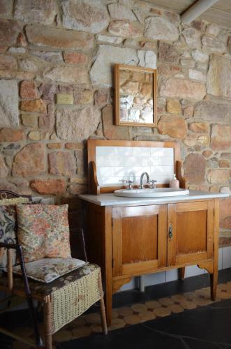 a bathroom with a sink and a stone wall at Trestrail Cottage Accommodation in Clare
