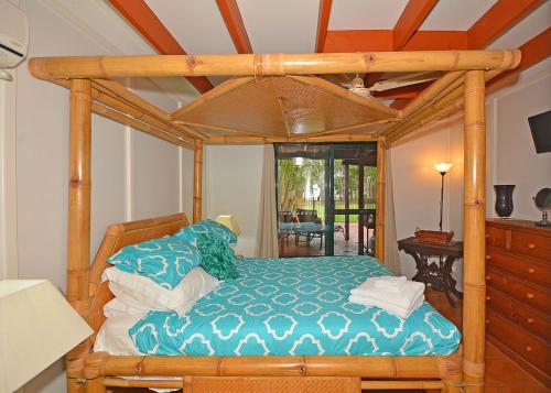 a bedroom with a bed with a wooden canopy at Bali on The Beach Absolute frontage-Lawn access in Toogoom