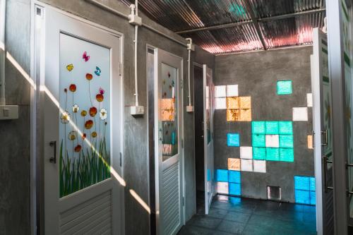 a hallway with a door and colorful tiles on the wall at Pomme Hostel Restaurant & Bar - Private Sleeping Cabins in Battambang