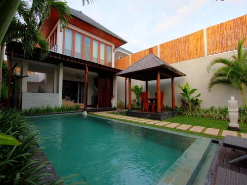 a swimming pool in front of a house at Grania Bali Villas in Seminyak