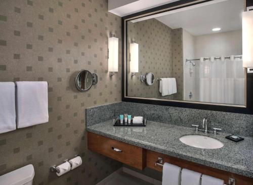 uma casa de banho com um lavatório e um espelho grande em Hyatt Regency Pittsburgh International Airport em Clinton