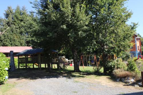 a park with a tree and a playground at Cabañas Santa Maria Pucon in Pucón