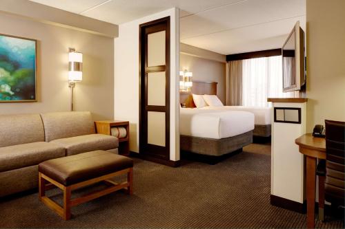 a hotel room with a bed and a couch at Hyatt Place Dallas North in Addison