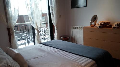 een slaapkamer met een bed en een raam met een balkon bij Descanso Termal in Ourense