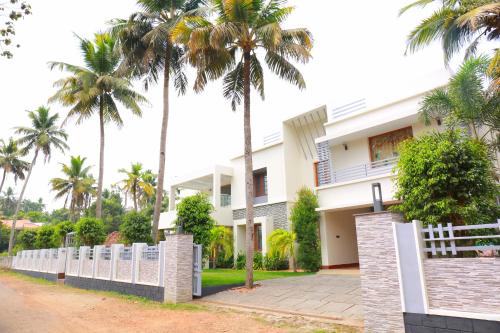 a house with palm trees in front of it at Shamrock Home Stay (5-Bedroom Bungalow) in Thiruvalla