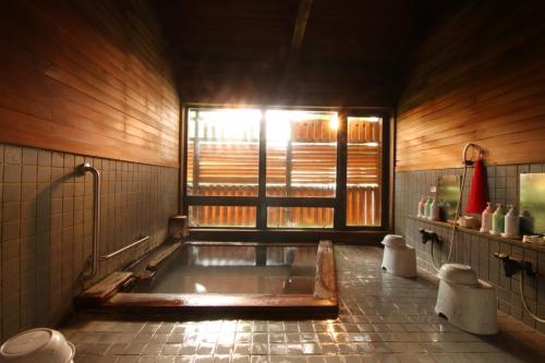 La salle de bains est pourvue d'une baignoire et d'une fenêtre. dans l'établissement Le Vert Zao, à Zao Onsen