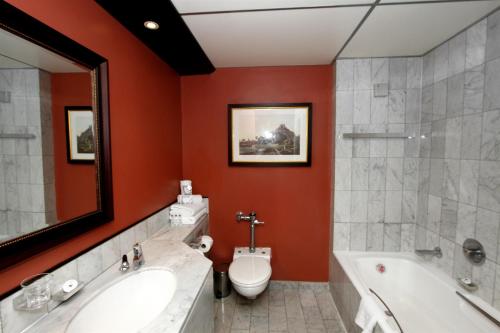 a bathroom with a tub and a toilet and a sink at The Royal Hotel by Coastlands Hotels & Resorts in Durban