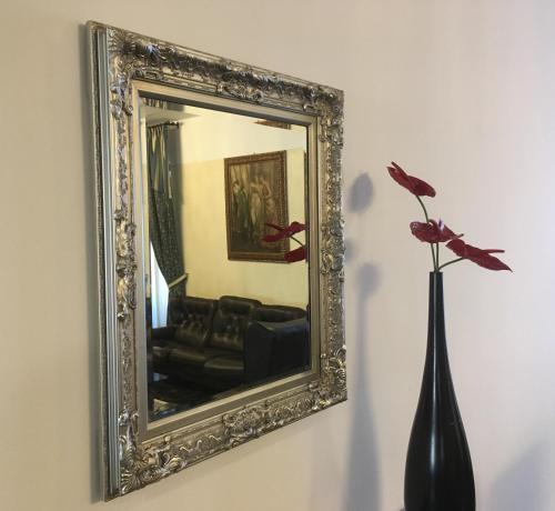 a mirror on a wall with a vase with a flower at Hotel Internazionale Gorizia in Gorizia