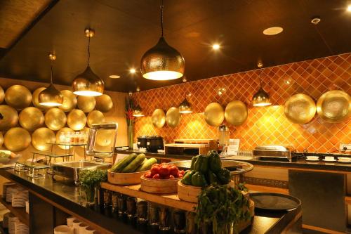 a kitchen with pots and pans and vegetables on a counter at Hotel Deccan Serai, HITEC CITY, HYDERABAD in Hyderabad