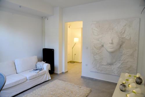a living room with a white couch and a painting on the wall at Acropolis At Your Door in Athens