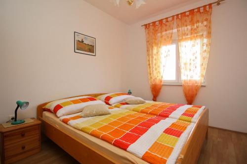 Un dormitorio con una cama con un edredón colorido y una ventana en Apartments Nikolic, en Šilo