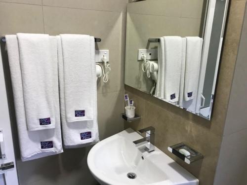 a bathroom with a sink and a mirror and towels at Lavendish Hills Kandy in Kandy