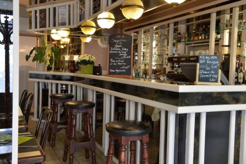 un bar con taburetes y una barra con bebidas en Logis Hotel Le Continental, en Châteauroux